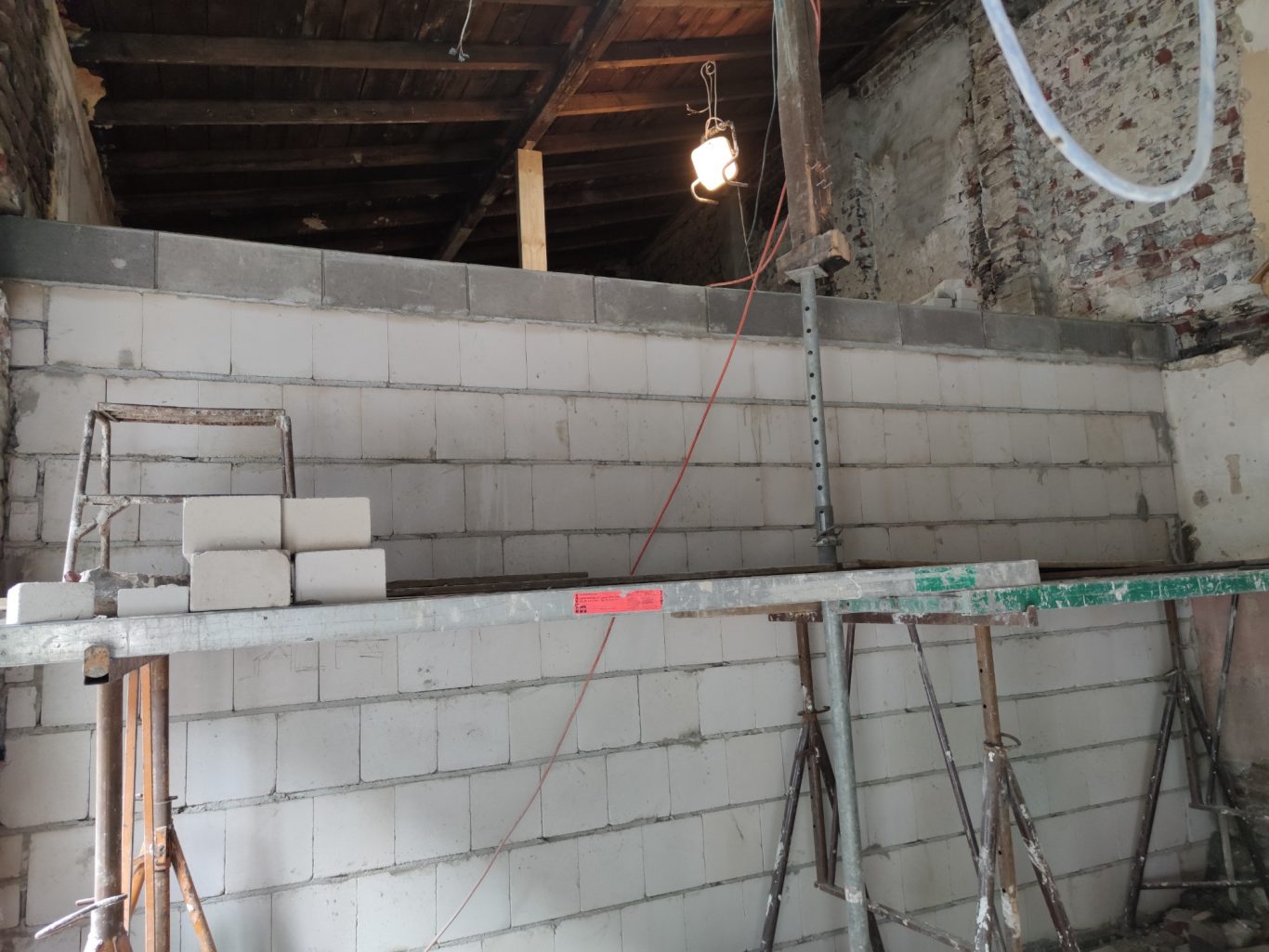 Ein Baugerüst mit Ziegeln und einer unvollendeten Wand in einem Raum.