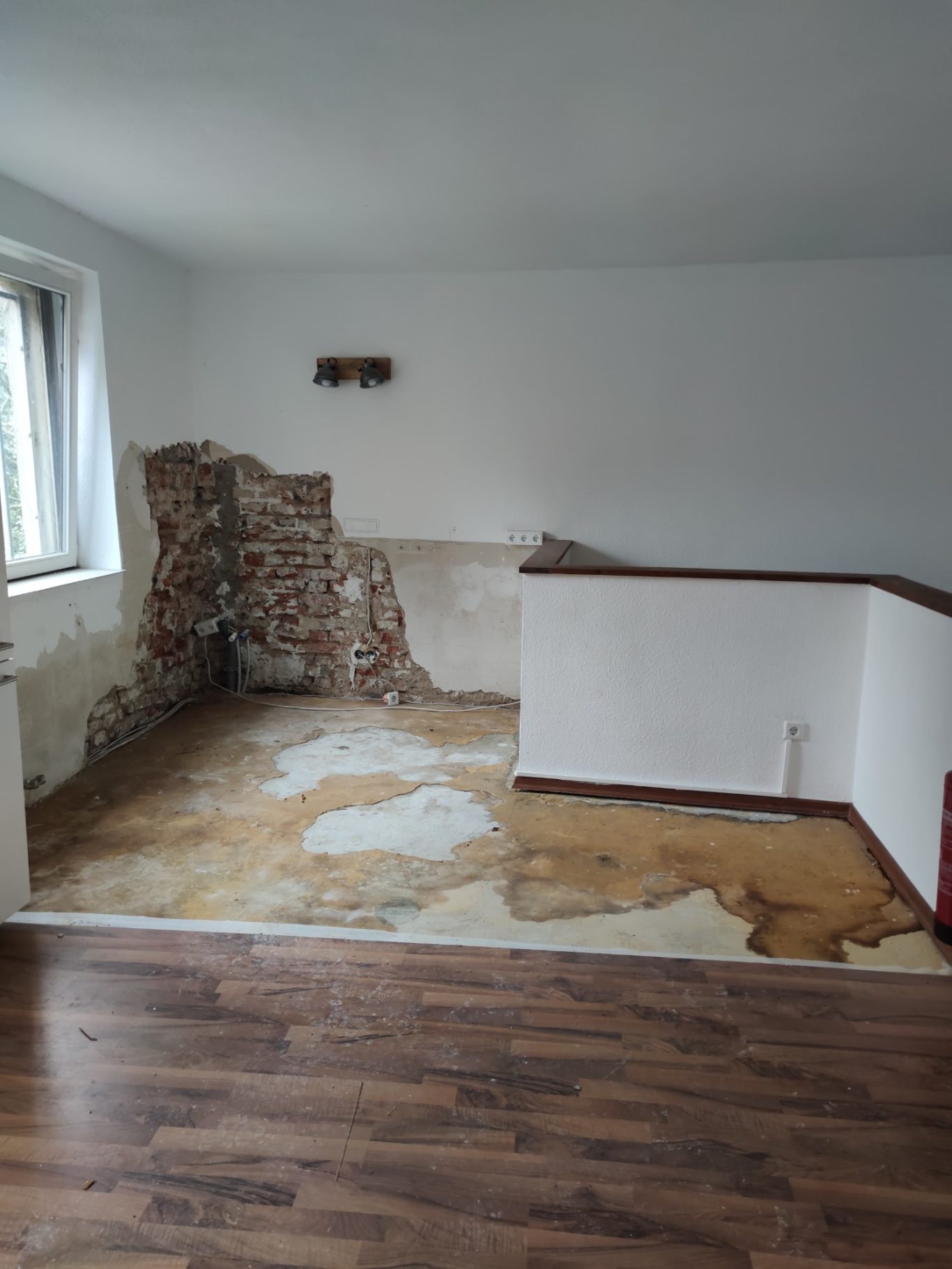 Unfertiger Raum mit einer schlecht verarbeiteten Wand und beschädigtem Bodenbelag.