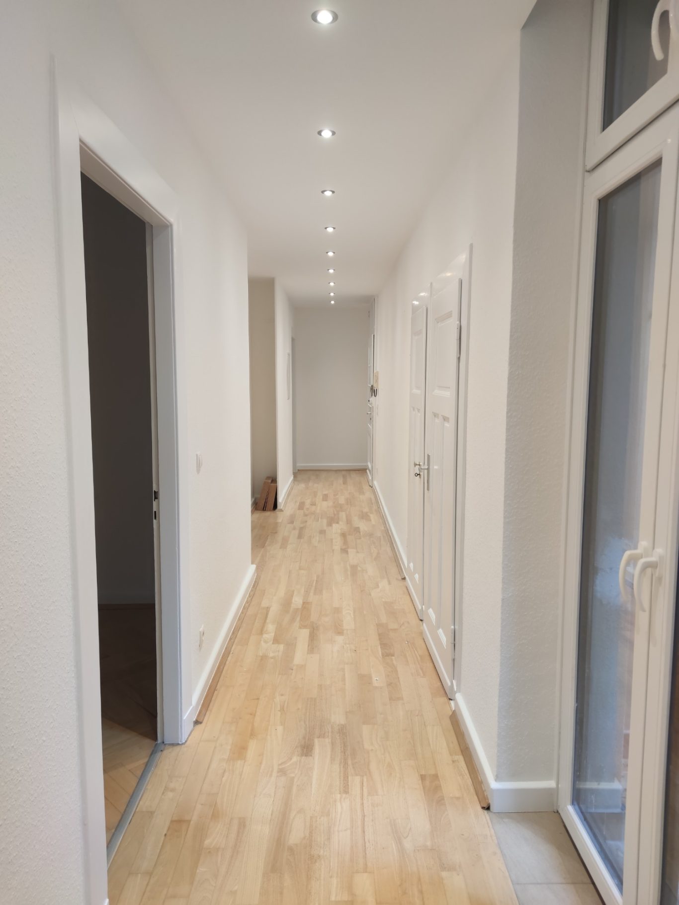 Langer, heller Flur mit Holzfußboden und Türen zu beiden Seiten.